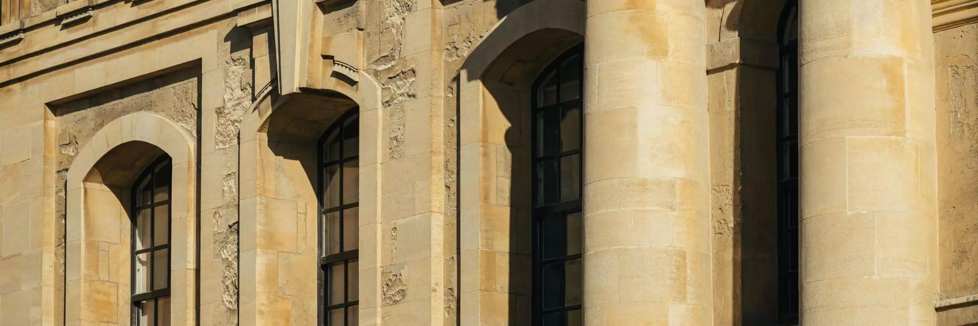 A close-up of columns and windows in an old building built from yellow stone