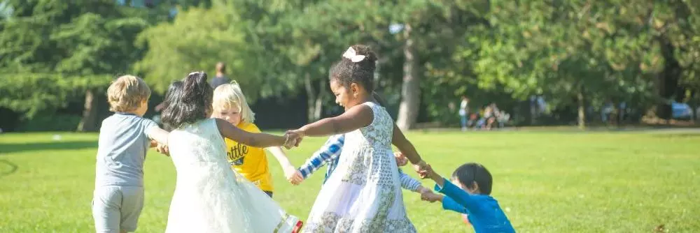 children playing in a green space with trees