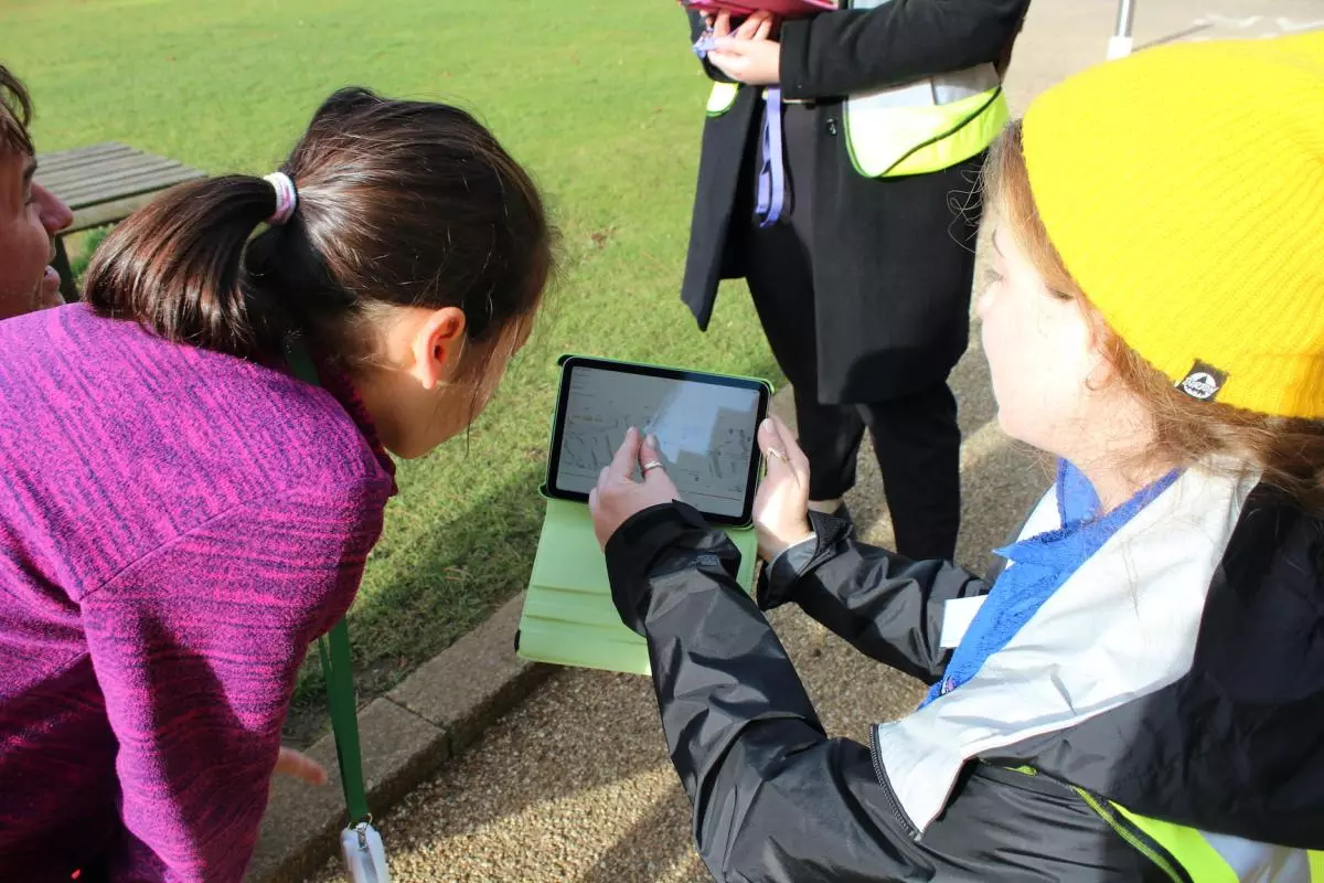 Researcher explains data on an ipad screen outside on a sunny day
