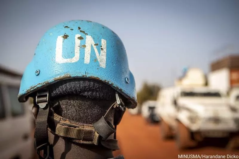 A person wears a blue UN Peacekeeper helmet