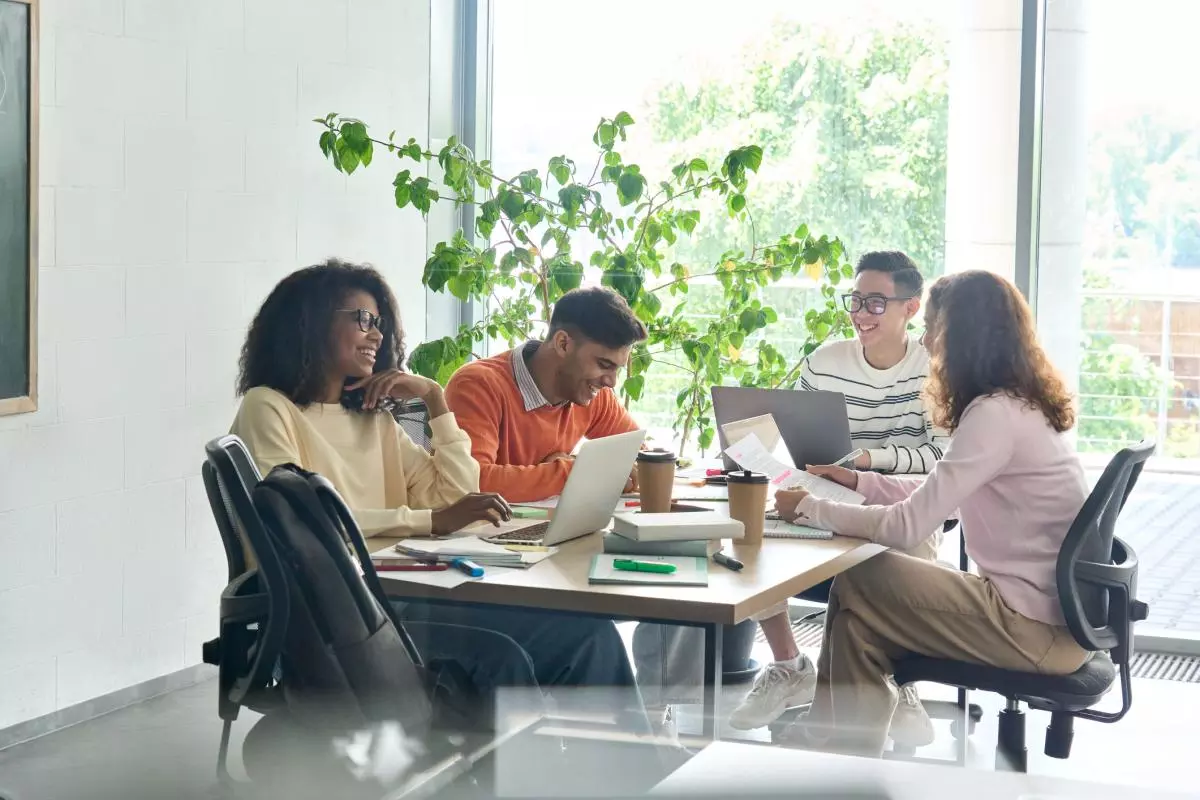 Young group of multicultural coworkers and researchers working together on a project in an office using laptops near a window.